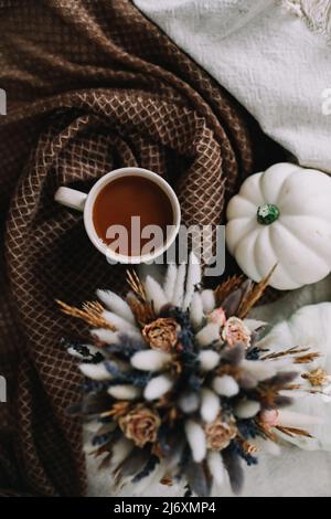Coffee cup with flowers and pumpkins on a cozy plaid. Autumn still life. Breakfast in bed. Good morning. Stylish autumn flat lay. Stock Photo