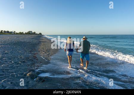 Old couple walking along beach in Florida Stock Photo