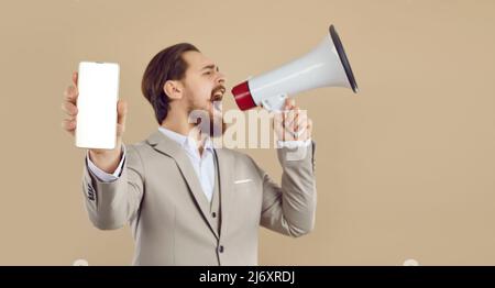 Man with loudspeaker makes loud announcement showing mobile phone with blank empty screen to camera. Stock Photo