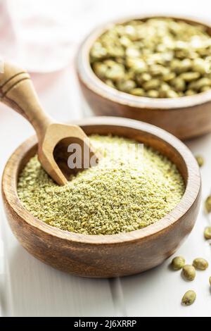 Ground green coffee in wooden bowl and unroasted coffee beans. Stock Photo
