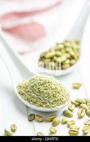 Ground green coffee and unroasted coffee beans on a white table. Stock Photo