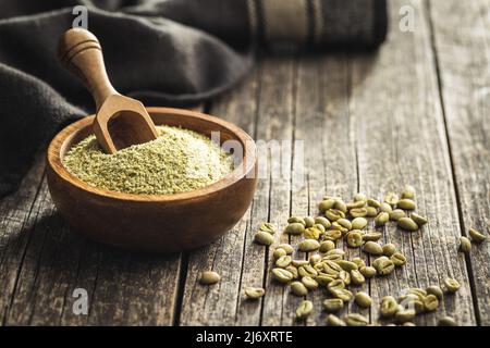 Ground green coffee in wooden bowl and unroasted coffee beans. Stock Photo