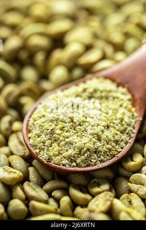 Ground green coffee in scoop and unroasted coffee beans. Stock Photo