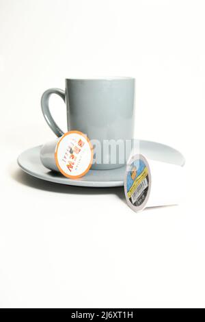 Gray coffee cup and used single-serve coffee K-cup pods isolated on white background Stock Photo