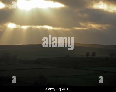 break in clouds produces dramatic evening sky over Crosby Ravensworth fell with silhouetted Winter trees - Cumbria, England, UK Stock Photo