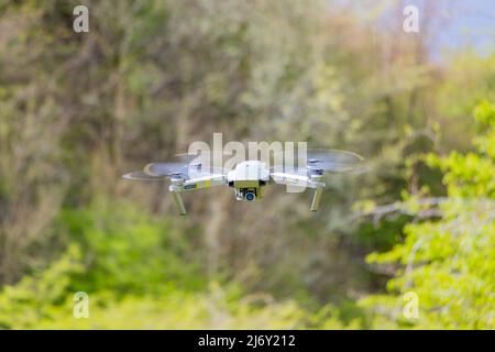 DJI Mavic Pro drone hovering against green grass bushes background Stock Photo