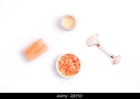 Himalayan pink salt for skrub, crystal rose quartz facial roller, handmade soap bar and cream in a jar. Natural skin care products isolated on white b Stock Photo