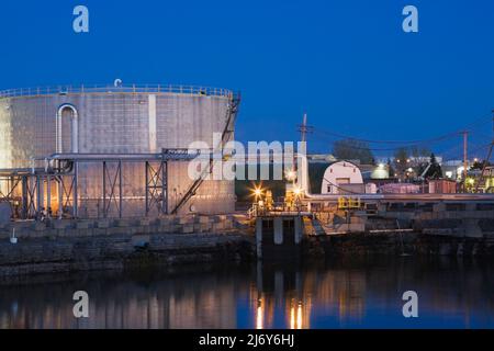 Oil storage tank at an oil and gas refinery illuminated at dusk, Montreal, Quebec, Canada. Stock Photo