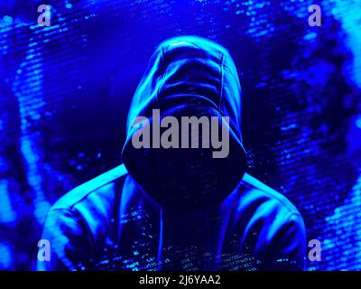 A hacker in shadow surrounded by computer code Stock Photo