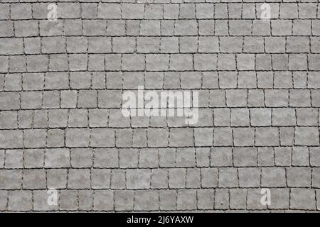 Gray color paving slabs in the pedestrian street sidewalk. Rough cobblestone pattern with many square shaped stones close up Stock Photo