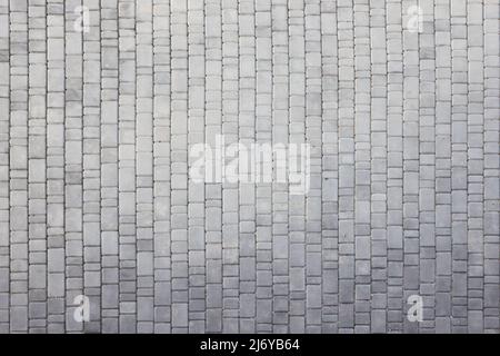 Gray color paving slabs in the pedestrian street sidewalk. Rough cobblestone pattern with many square shaped stones close up Stock Photo