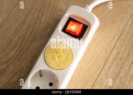 Bitcoin lying on a power supply socket. Crypto currency BTC which is mined under high power consumption due to the amount of mining effort. Stock Photo