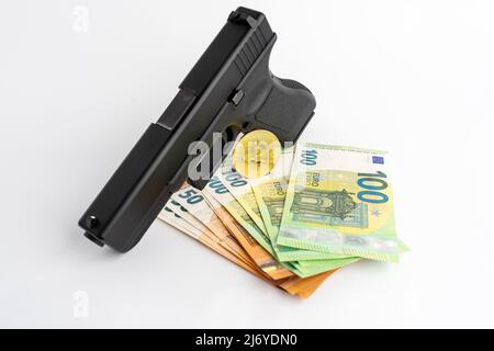 Gun, Bitcoin and Euro banknotes on a white background. Symbols of crime in the darknet and real world. Cash money and BTC used as payment. Stock Photo
