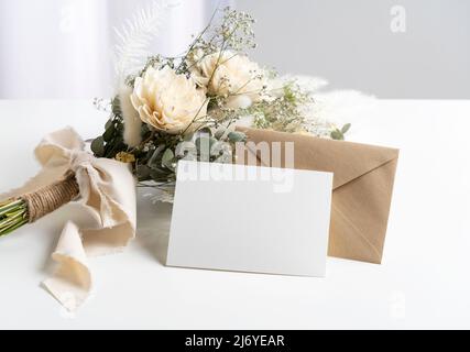 Dried flower bouquets and blank message cards placed on white tables. Wedding and celebration concept. Stock Photo