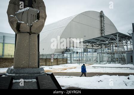 February 19, 2018, Pripyat, Ukraine: A Chernobyl nuclear power plant worker walks in front of the new sarcophagus covering reactor number 4. HBO, with its series Chernobyl, has managed to get a large percentage of people around the world interested in the most serious nuclear accident in history, to such an extent that thousands of tourists come to Ukraine to learn first-hand about the consequences of the tragedy and take some souvenirs. With its series Chernobyl, HBO has managed to get a large percentage of people interested in the most severe nuclear accident in history, to such an extent th Stock Photo