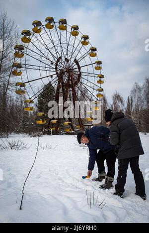 February 19, 2018, Pripyat, Ukraine: A Chernobyl guide shows radiation levels to a tourist in the vicinity of the famous Pripyat Ferris wheel. HBO, with its series Chernobyl, has managed to get a large percentage of people around the world interested in the most serious nuclear accident in history, to such an extent that thousands of tourists come to Ukraine to learn first-hand about the consequences of the tragedy and take some souvenirs. With its series Chernobyl, HBO has managed to get a large percentage of people interested in the most severe nuclear accident in history, to such an extent Stock Photo