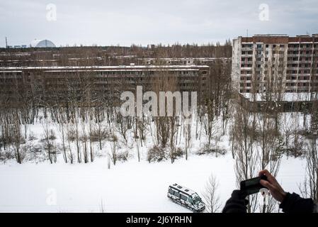 February 19, 2018, Pripyat, Ukraine: A tourist photographs with his phone a panoramic view of Pripyat. HBO, with its series Chernobyl, has managed to get a large percentage of people around the world interested in the most serious nuclear accident in history, to such an extent that thousands of tourists come to Ukraine to learn first-hand about the consequences of the tragedy and take some souvenirs. With its series Chernobyl, HBO has managed to get a large percentage of people interested in the most severe nuclear accident in history, to such an extent that thousands of tourists come to Ukrai Stock Photo