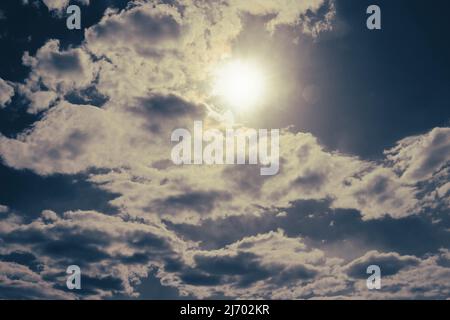 The sun peeks out from behind cumulus clouds. Anxious mood. Stock Photo