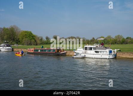 Narrow boat and two cabin cruisers moored bank side of The Brocas meadow on the Eton side of the River Thames. Windsor, England, UK. Stock Photo