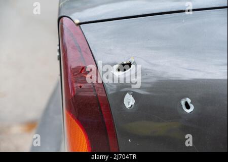 Close-up of the rear of the shelled car. Sedan with through holes from shrapnel. The war in Ukraine 2022. Russian aggression. The shelling of civilian Stock Photo