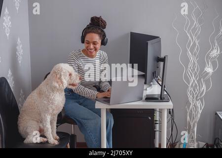 Young pretty female programmer writing program code on computer sitting at home Stock Photo