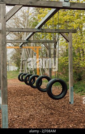 Tires from the wheels hang on chains in the park on a sunny day Stock Photo