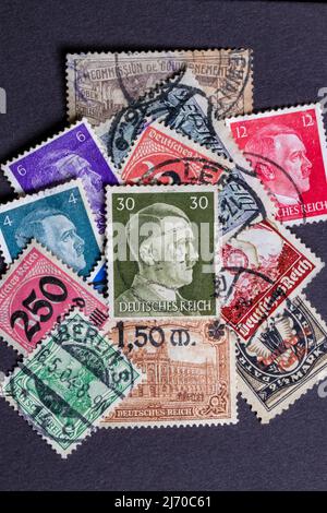Potsdam, Germany - APR 26, 2022. A stack of old German stamps from the Third Reich and on it a stamp with printed portrait of Adolf Hitler, the leader Stock Photo
