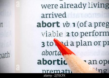 Red pencil on an opened dictionary and abort word, concept picture Stock Photo