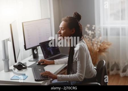 Side view of mixed-race young professional concentrated skilled web expert working on computer Stock Photo