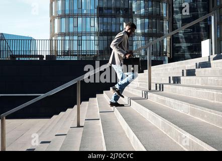 African American manager with case running up the stairs towards modern office building on sunny morning Stock Photo