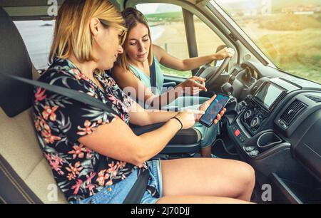 Friends looking gps on the mobile during a campervan trip Stock Photo