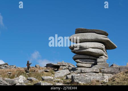 A walker photographing The Cheesewring a huge granite rock stack formed by glacial action on the summit of Stowes Hill on Bodmin Moor in Cornwall. Stock Photo