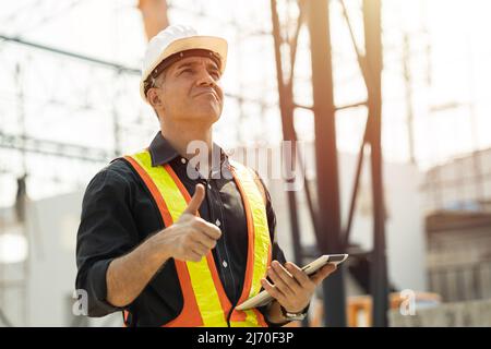 Professional Caucasian Engineer male builder working at construction site work outdoor with safety thumbs up. Stock Photo