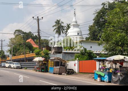 Malabe, Sri Lanka - December 4, 2021: Malabe street view with the  dome of the Sri Sudharshanarama Purana Viharaya on a background, main temple for Bu Stock Photo