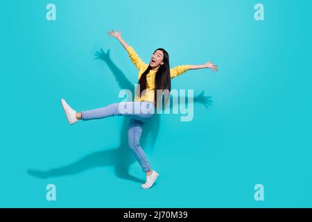 Full length photo of impressed funky lady dressed yellow sweater dancing walking empty space isolated turquoise color background Stock Photo
