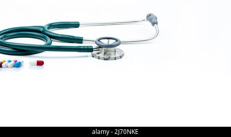 Green stethoscope and capsule pills on white background. Health checkup. Cardiology doctor equipment for heartbeat test. Healthcare and medical. Stock Photo