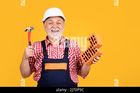 happy mature man worker in helmet on yellow background Stock Photo