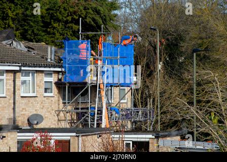 Men on scaffolding adjacent to roof repairs they are working on Stock Photo