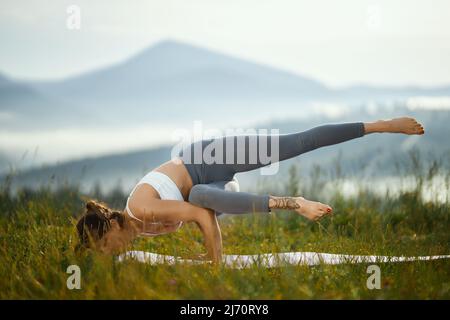 Woman doing yoga in Hero pose in mountains - a Royalty Free Stock Photo  from Photocase