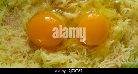 Broken chicken eggs and grated potatoes. food, potato pancakes, dish Stock Photo