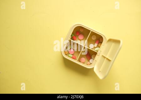 close up of medical pills in a pill box on yellow background  Stock Photo