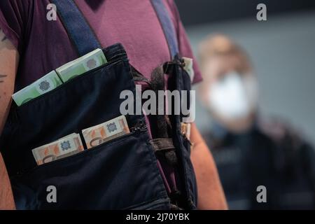 05 May 2022, Hessen, Frankfurt/Main: A customs employee wears a cash vest during the annual press conference of the Frankfurt Main Customs Office at Frankfurt Airport for the presentation. Photo: Sebastian Gollnow/dpa Stock Photo