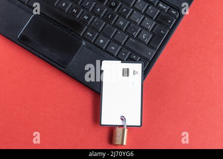 Credit card with padlock on top of a laptop with red background. Concept of expense control. Stock Photo