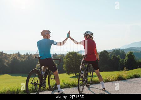 Road cyclists couple taking a ride break along a scenic cycling route enjoying stunning sights and giving high five Stock Photo