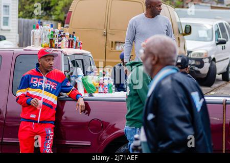 NEW ORLEANS, LA, USA - MARCH 17, 2019: Men standing in and around pickup truck selling alcoholic drinks to parade goers in Central City neighborhood Stock Photo