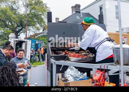 NEW ORLEANS, LA, USA - MARCH 17, 2019: Woman cooking meat on l outdoor grill in Central City as part of pre-Mardi Gras Indian parade on Super Suday Stock Photo
