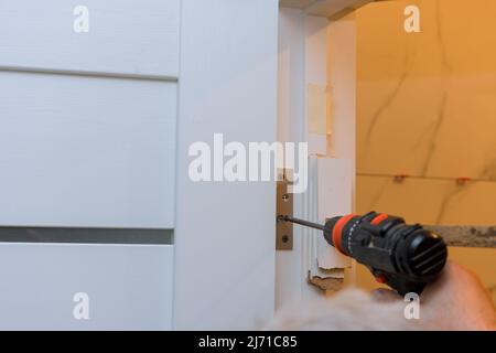 Process of installation stainless door hinges on a white wood door Stock Photo