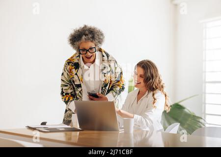Happy businesswomen smiling cheerfully during a video call with their business colleagues. Two diverse businesswomen having an online meeting in a wom Stock Photo