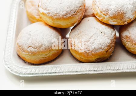 Berliner Pfannkuchen, a German donut, traditional yeast dough deep fried filled with chocolate cream and sprinkled with powdered sugar, sweetness on a Stock Photo