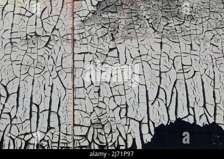 Cracked adhesive plastic film layer on glass surface. Grungy background texture. Stock Photo